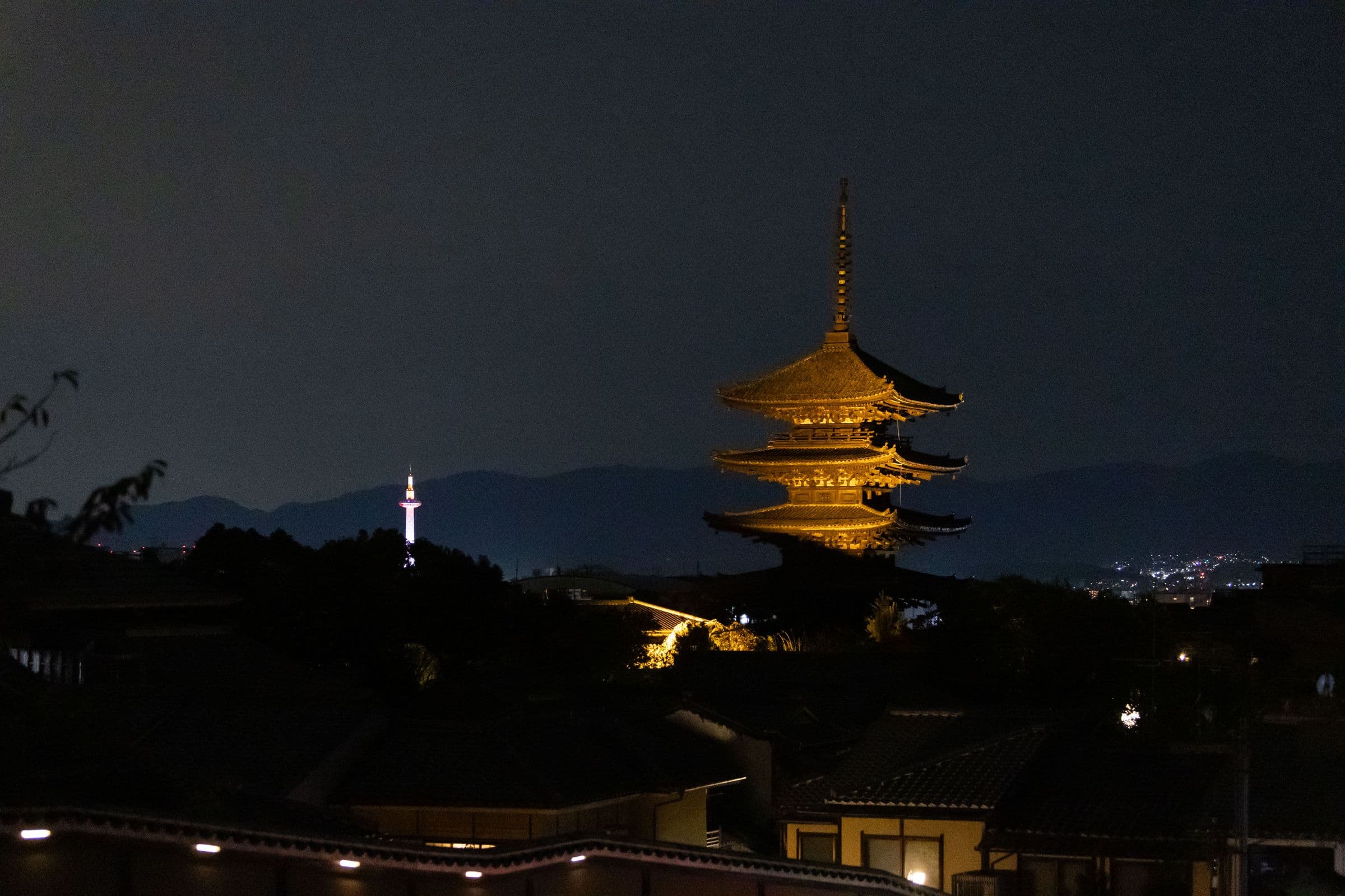 A lit pagoda above Kyoto at night