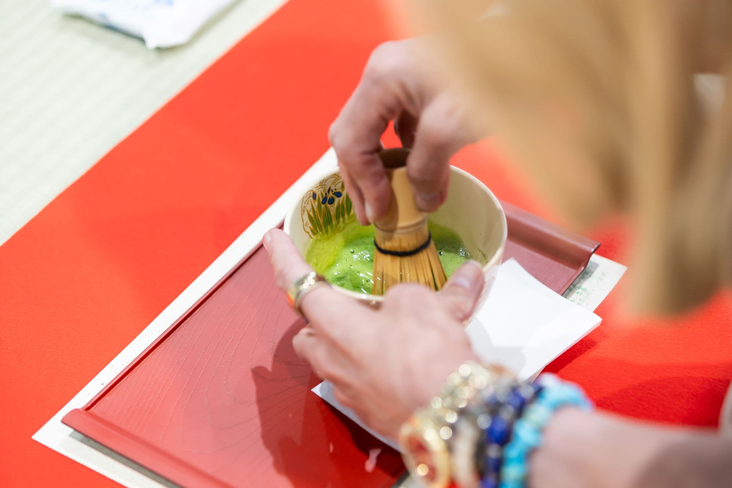 Hands whisking matcha in a tea bowl